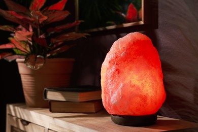 Photo of Himalayan salt lamp on wooden table near brown wall indoors