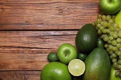 Many different fresh fruits and grapes on wooden table, flat lay. Space for text