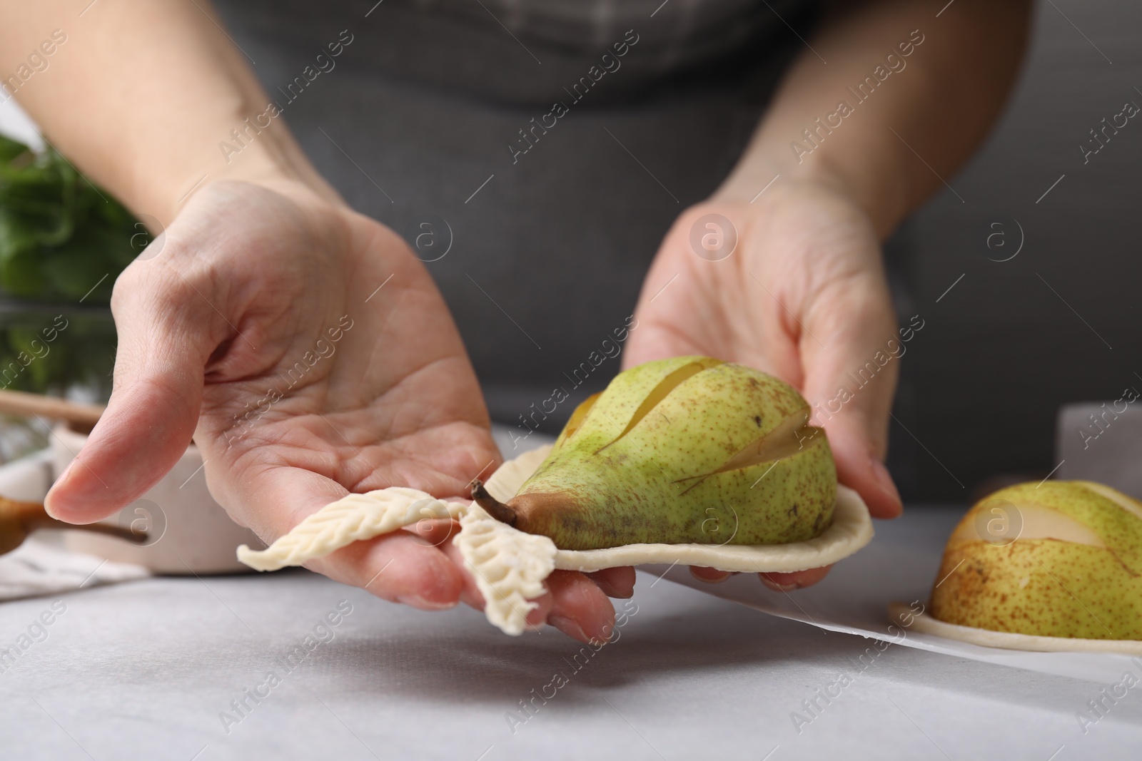 Photo of Woman making pastry with dough and fresh pears at white table, closeup