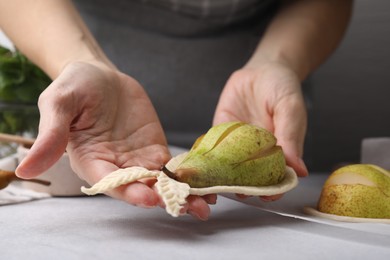 Woman making pastry with dough and fresh pears at white table, closeup