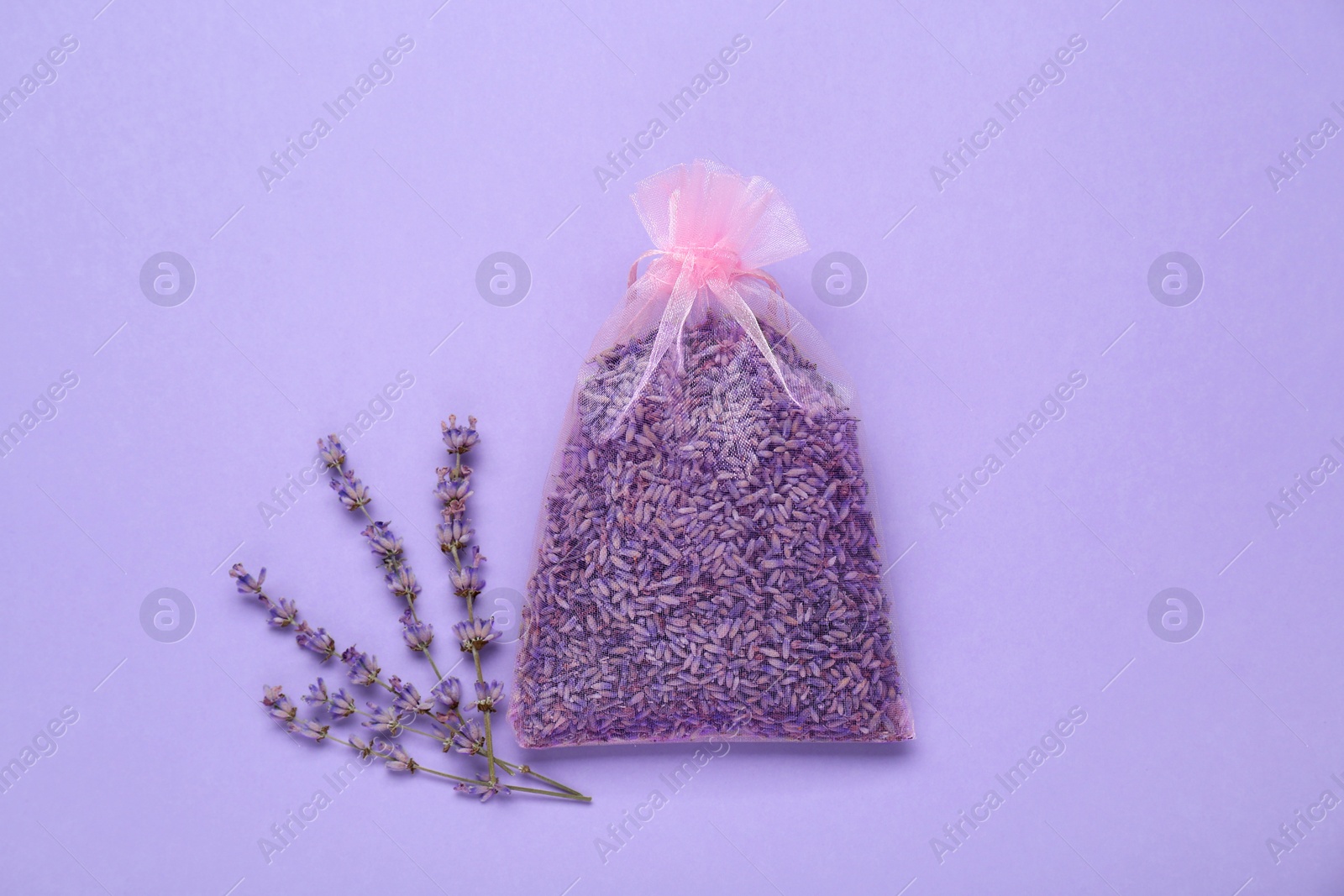 Photo of Scented sachet with dried lavender flowers on lilac background, flat lay