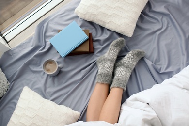 Young woman lying on bed, closeup view of legs. Winter atmosphere