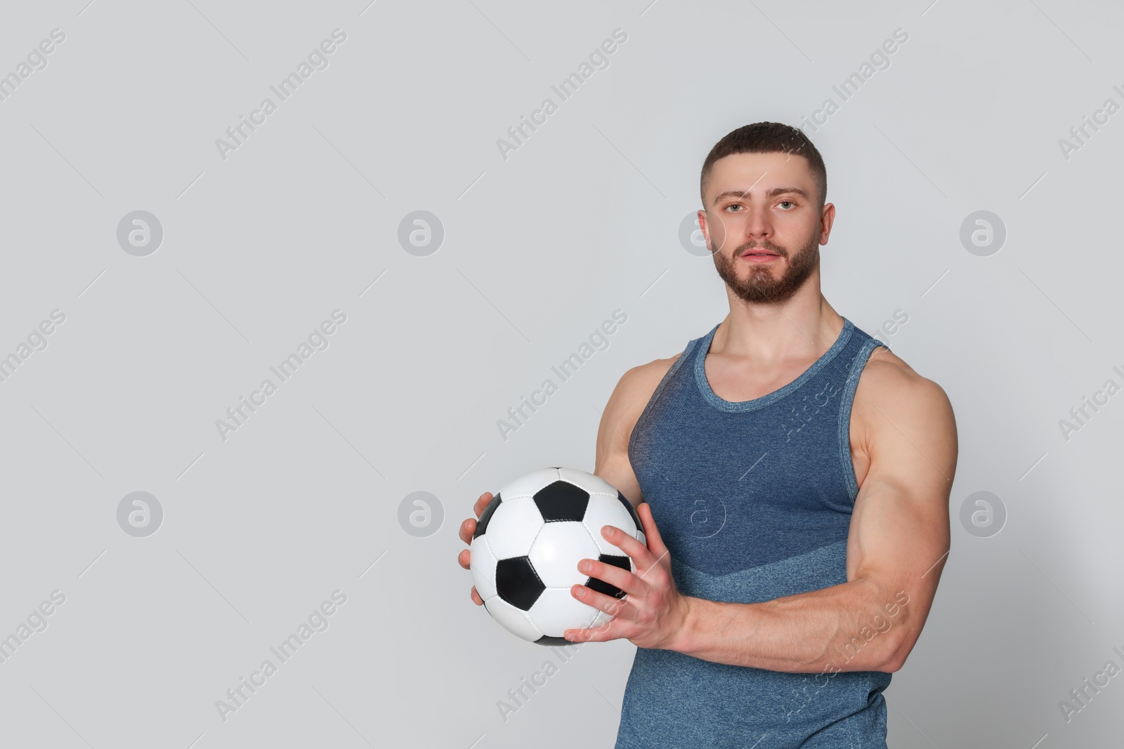 Photo of Athletic young man with soccer ball on light grey background. Space for text