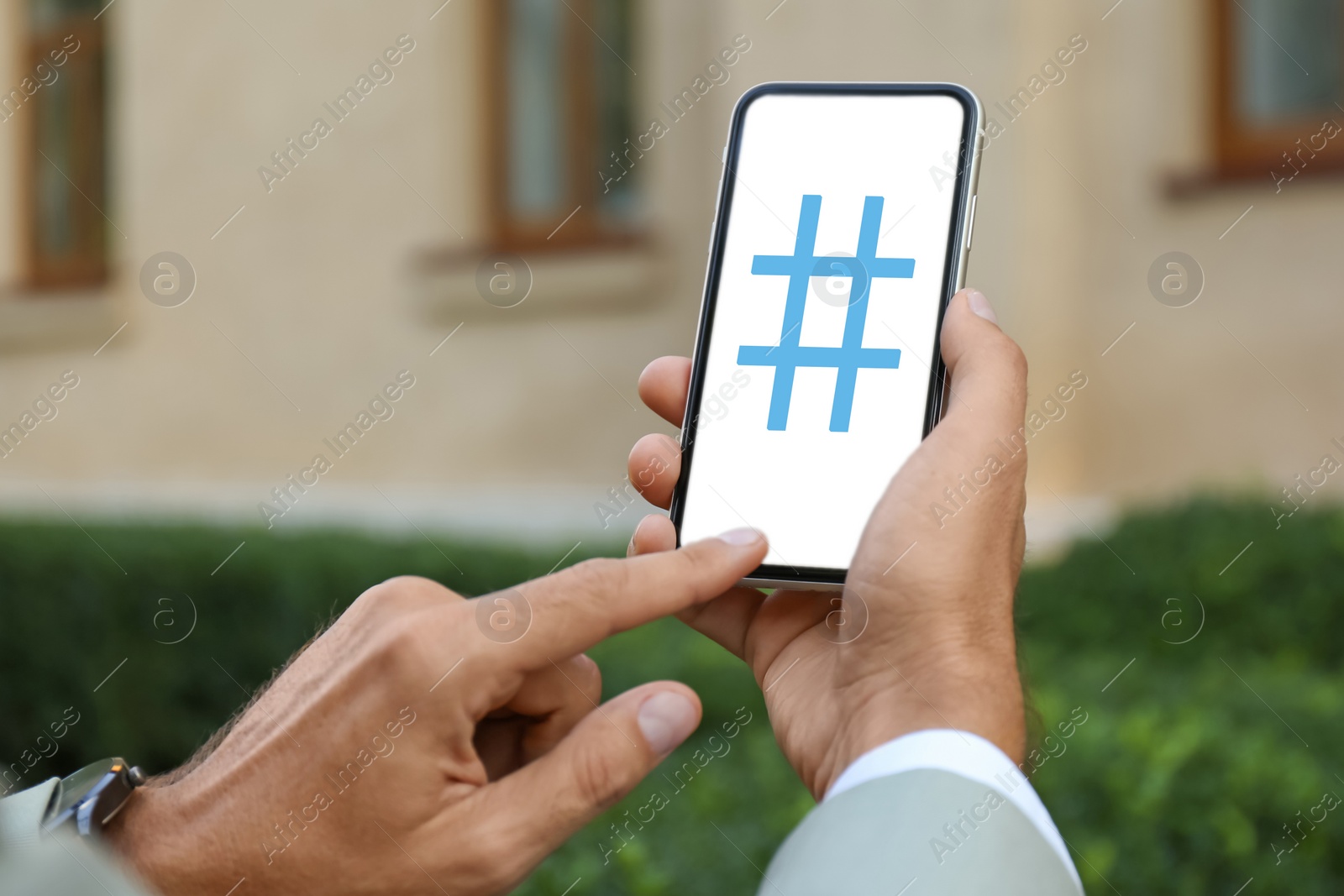 Image of Man using modern smartphone with hashtag symbol on screen outdoors, closeup