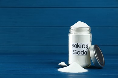 Photo of Jar and spoon with baking soda on blue wooden table. Space for text