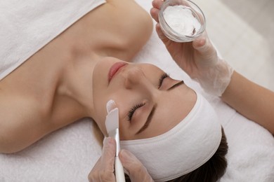 Photo of Young woman during face peeling procedure in salon