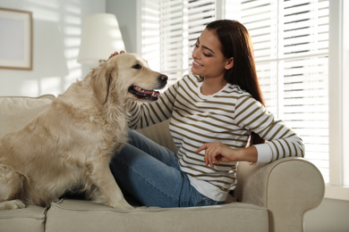 Photo of Young woman and her Golden Retriever on sofa at home. Adorable pet