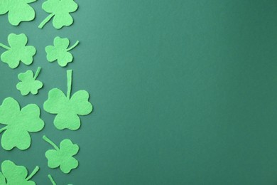 Photo of St. Patrick's day. Decorative clover leaves on green background, flat lay. Space for text