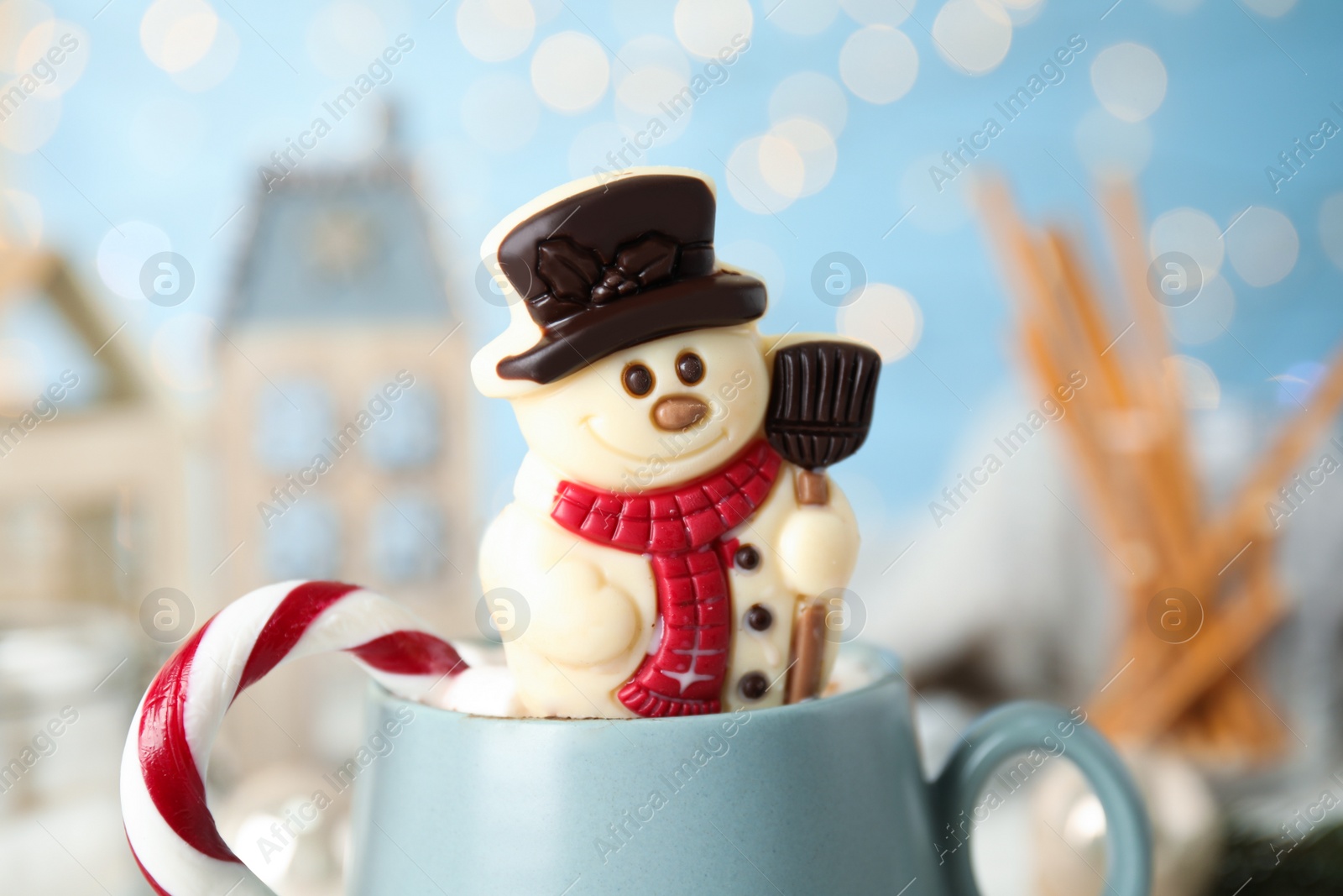 Photo of Funny chocolate snowman candy in cup of hot drink, closeup