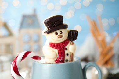 Funny chocolate snowman candy in cup of hot drink, closeup