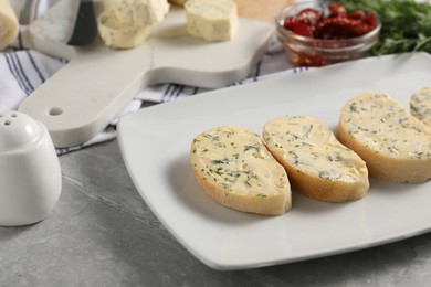 Photo of Tasty butter with dill and bread on grey marble table, closeup