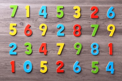 Photo of Colorful numbers on wooden school desk, flat lay