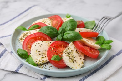 Caprese salad with tomatoes, mozzarella, basil and spices on table, closeup