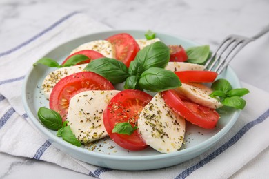 Photo of Caprese salad with tomatoes, mozzarella, basil and spices on table, closeup