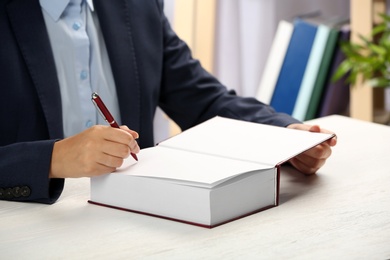 Writer signing autograph in book at table, closeup