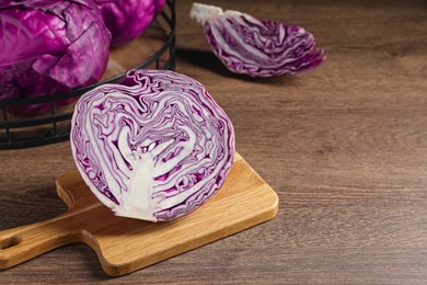 Photo of Whole and cut fresh red cabbage on wooden table, space for text