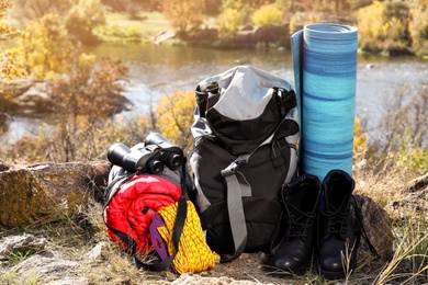 Photo of Set of camping equipment with sleeping bag on ground outdoors