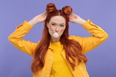 Photo of Portraitbeautiful woman with bright makeup blowing bubble gum on violet background