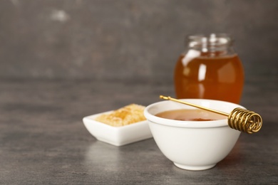 Photo of Bowl of tasty fresh honey and dipper on table
