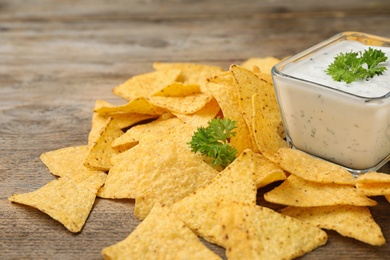 Mexican nacho chips with sauce on wooden table