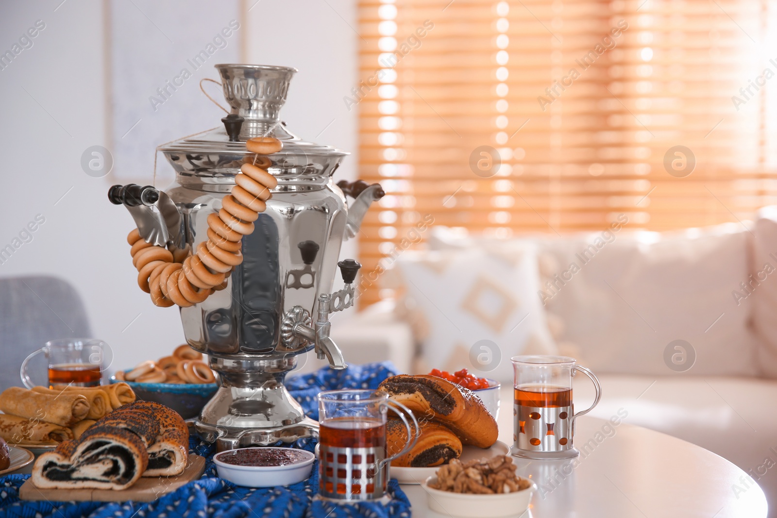 Photo of Traditional Russian samovar with treats on white table at home