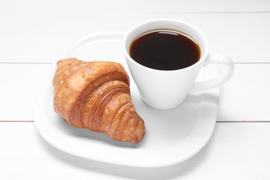 Photo of Tasty breakfast. Cup of coffee and croissant on white wooden table