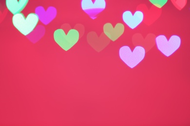 Photo of Blurred view of beautiful heart shaped lights on color background. Space for text