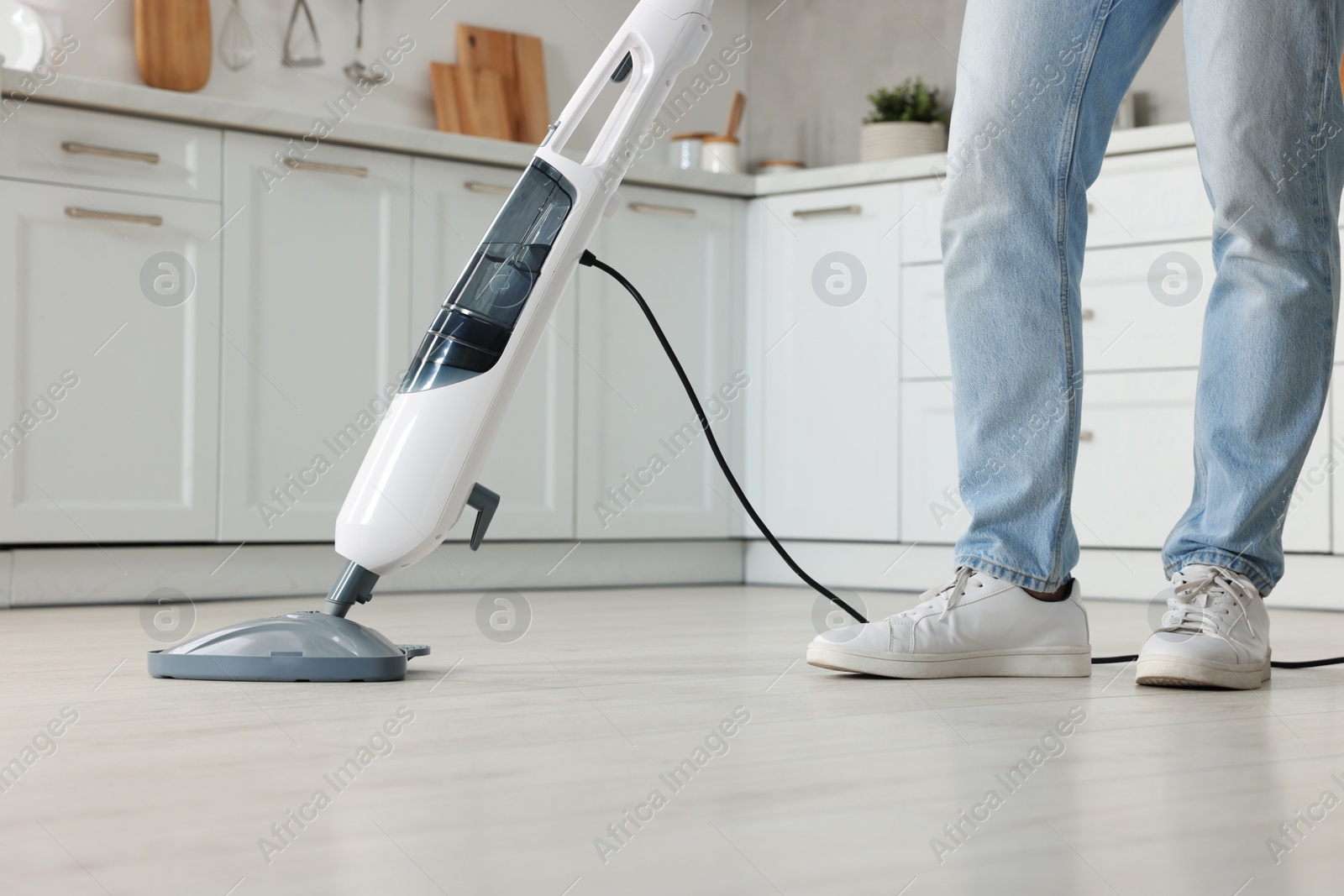 Photo of Man cleaning floor with steam mop at home, closeup