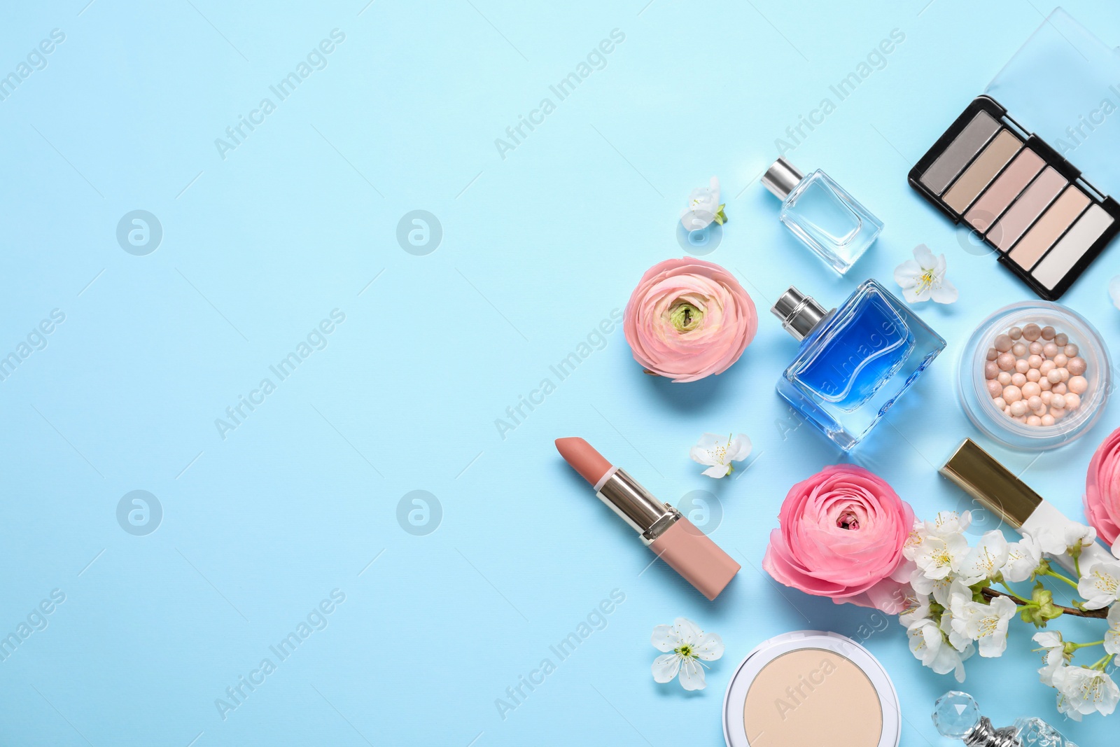 Photo of Flat lay composition with different makeup products and beautiful spring flowers on light blue background, space for text