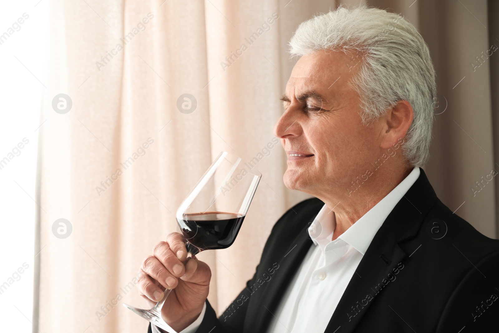 Photo of Senior man with glass of wine indoors. Space for text