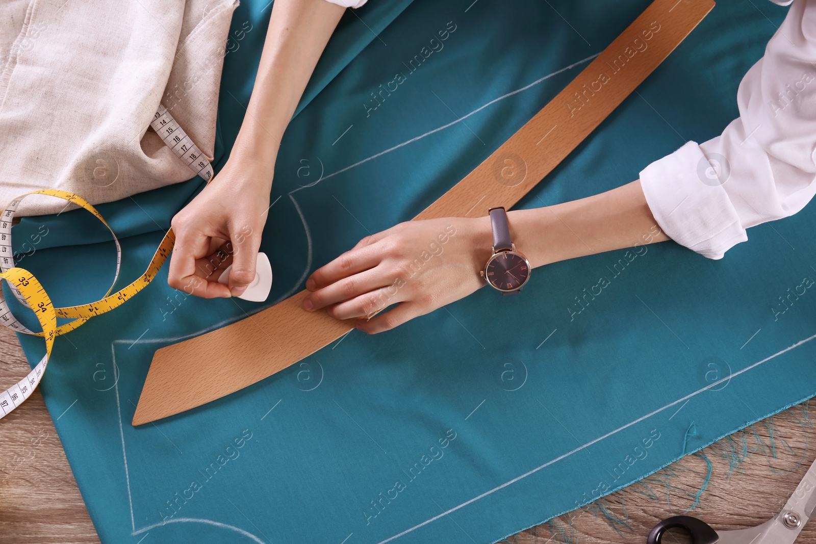 Photo of Tailor working with cloth at table in atelier, top view