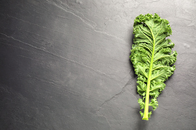 Photo of Fresh kale leaf on black table, top view. Space for text