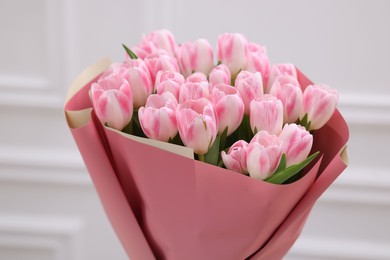 Beautiful bouquet of fresh pink tulips near white wall