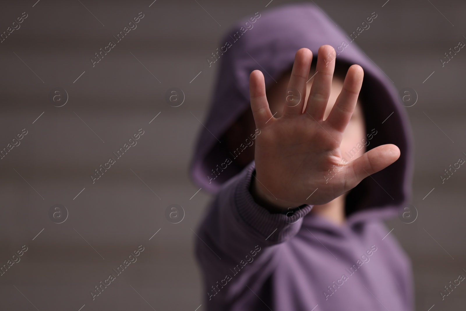 Photo of Child abuse. Boy doing stop gesture on light background, selective focus. Space for text