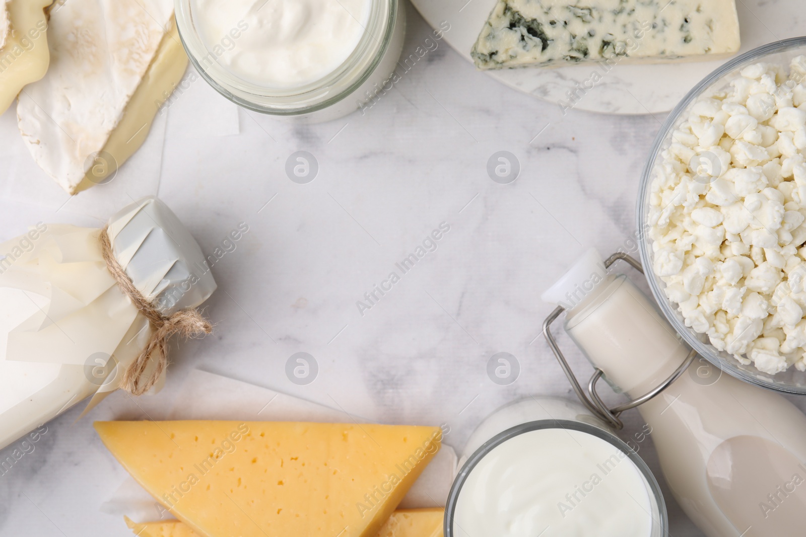 Photo of Frame of different fresh dairy products on white marble table, flat lay. Space for text