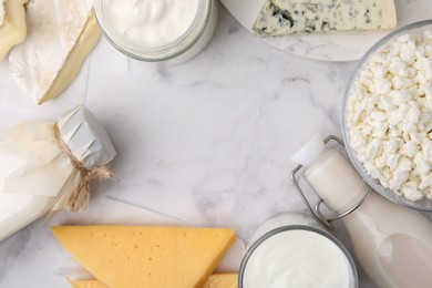 Frame of different fresh dairy products on white marble table, flat lay. Space for text