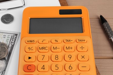 Orange calculator, money and pen on table, closeup. Retirement concept