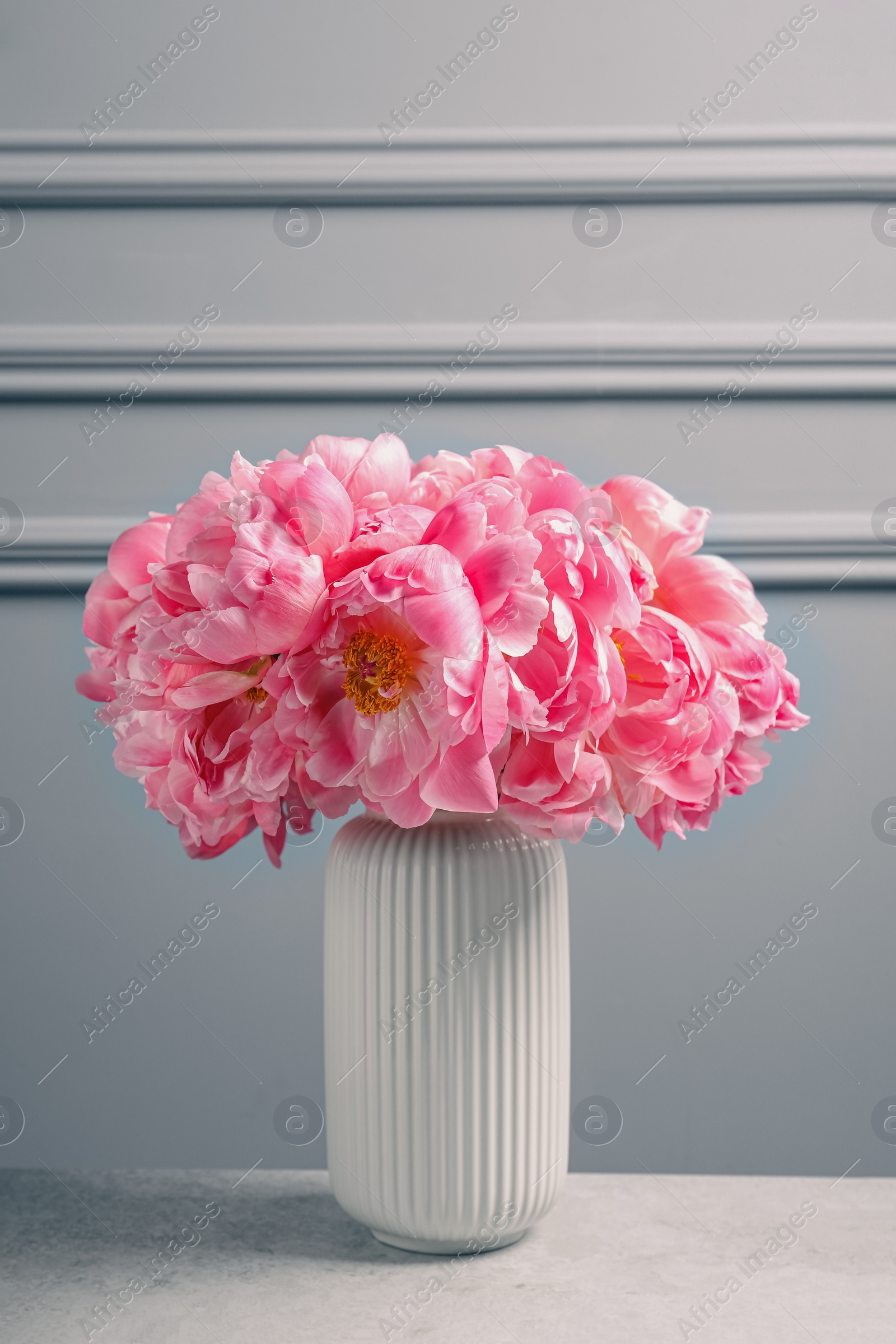 Photo of Beautiful bouquet of pink peonies in vase on table near grey wall