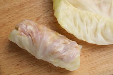 Photo of Uncooked stuffed cabbage roll on wooden board, top view