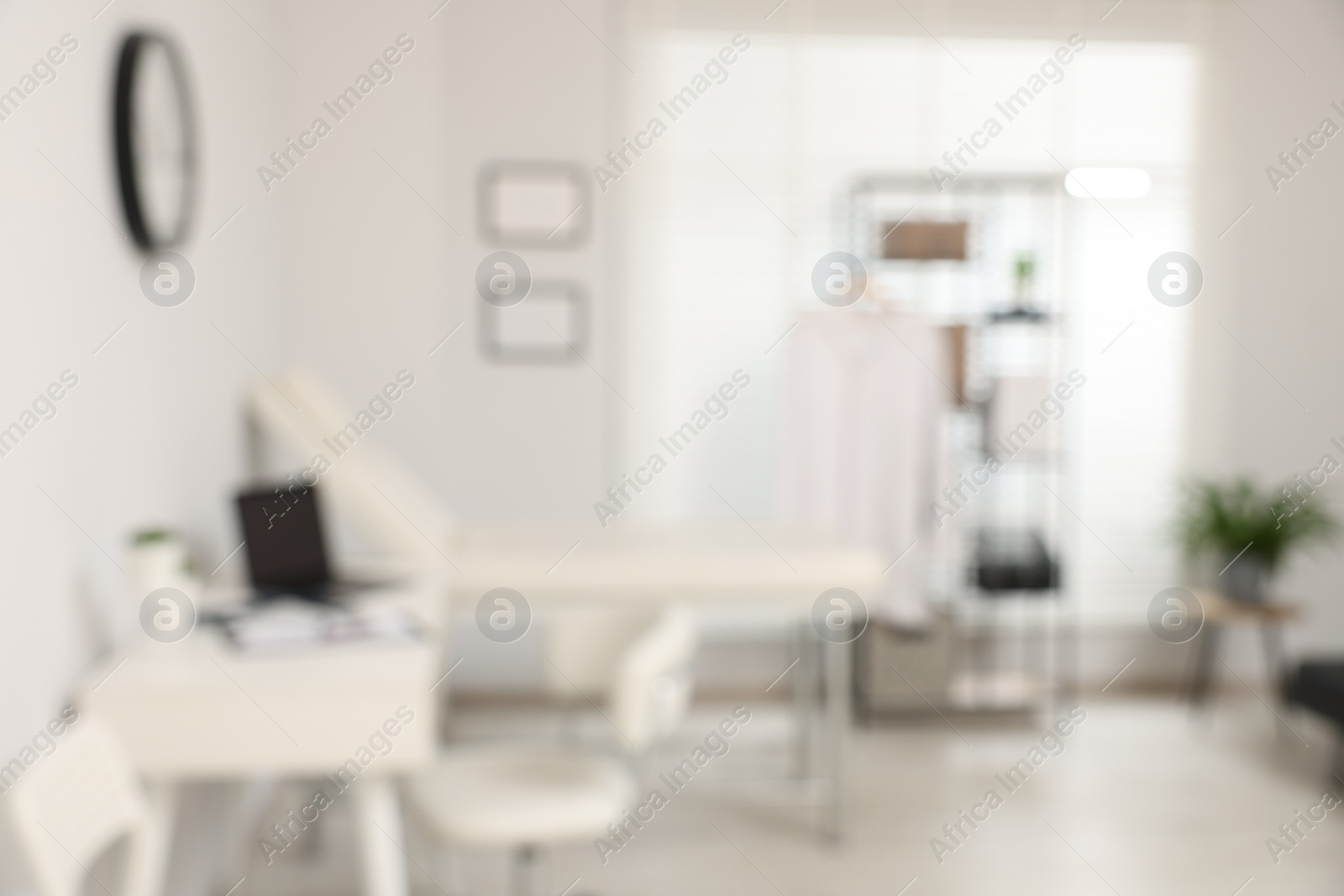 Photo of Blurred view of modern medical office with doctor's workplace and examination table in clinic