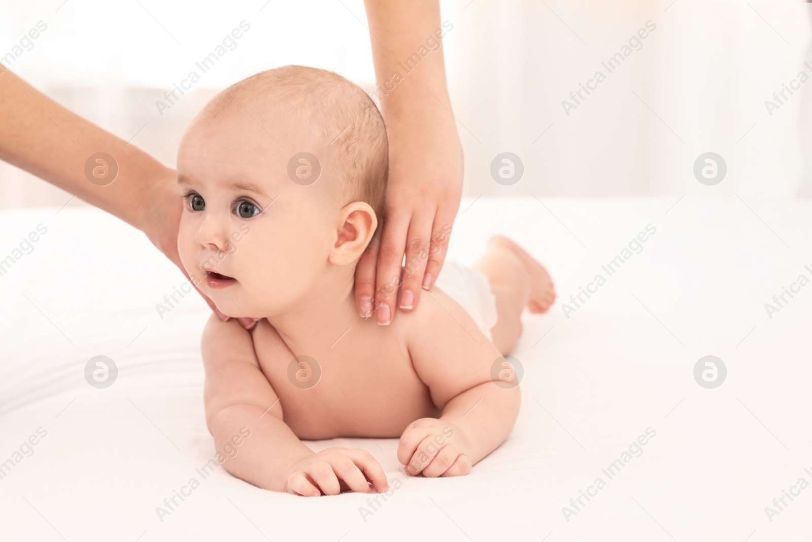 Photo of Mother and her cute child on bed indoors, space for text. Baby massage and exercises