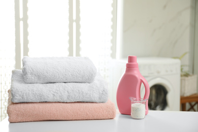 Photo of Clean towels and detergents on table in laundry room