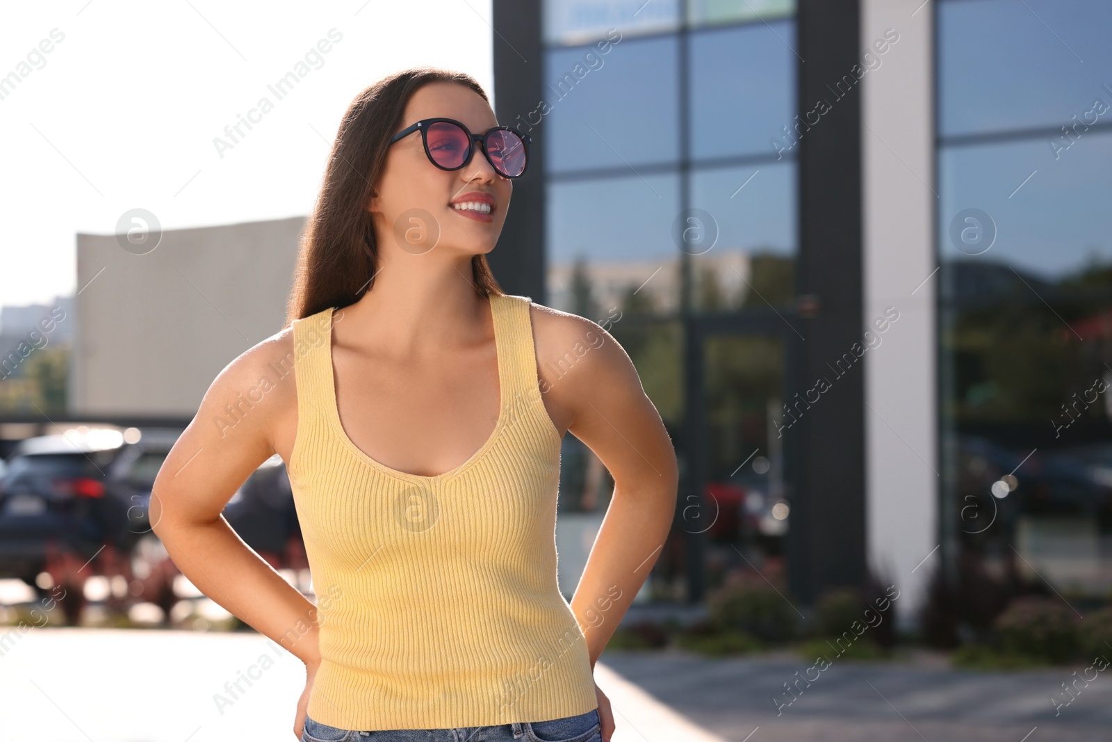 Photo of Beautiful smiling woman in sunglasses on city street, space for text