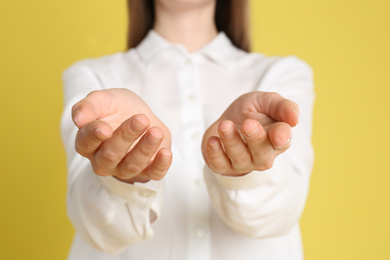 Photo of Young woman against yellow background, focus on hands