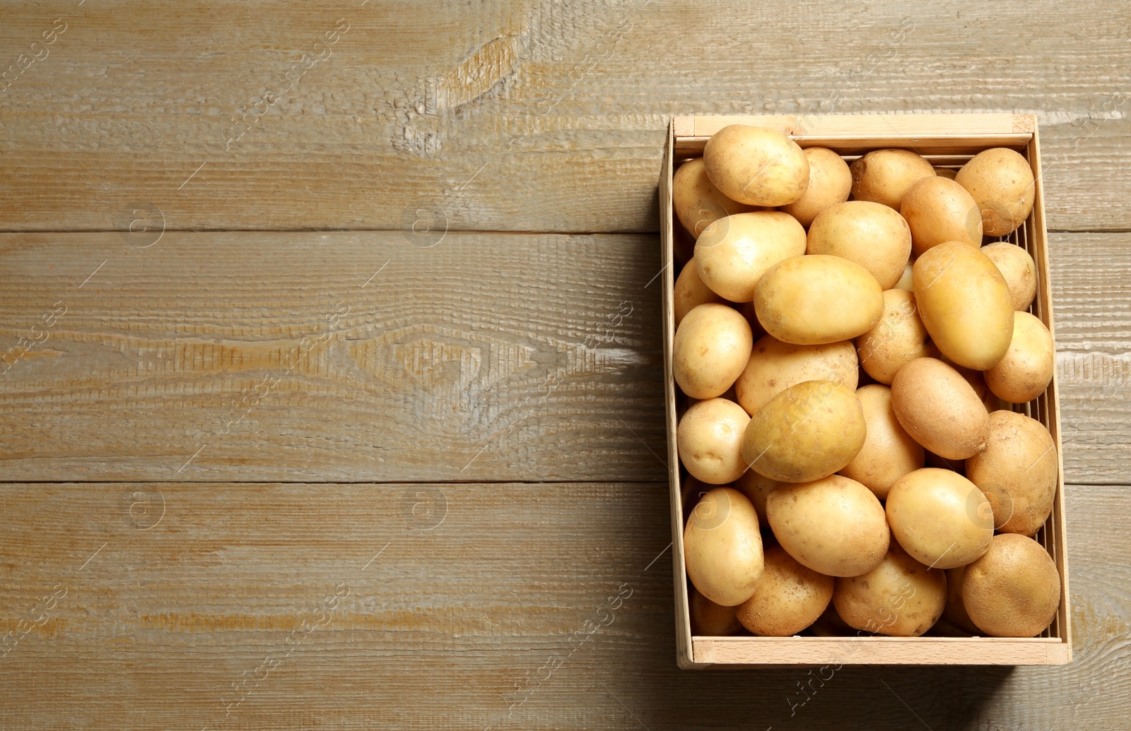 Photo of Raw fresh organic potatoes on wooden background, top view. Space for text