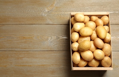 Raw fresh organic potatoes on wooden background, top view. Space for text