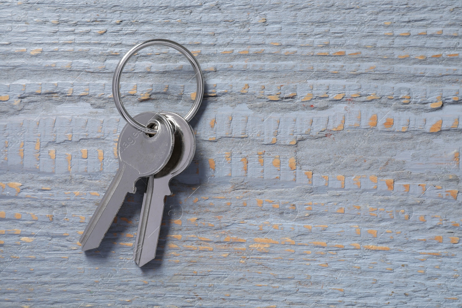 Photo of Keys with ring on grey wooden table, top view. Space for text