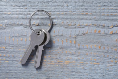 Keys with ring on grey wooden table, top view. Space for text