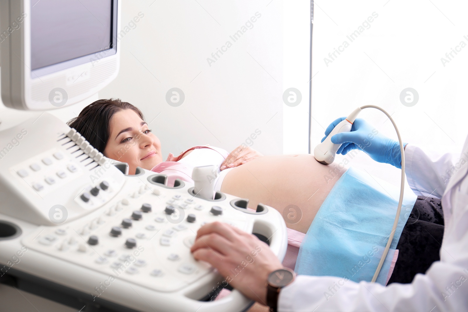 Photo of Young pregnant woman undergoing ultrasound scan in clinic