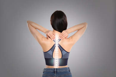 Image of Woman suffering from pain in spine on grey background